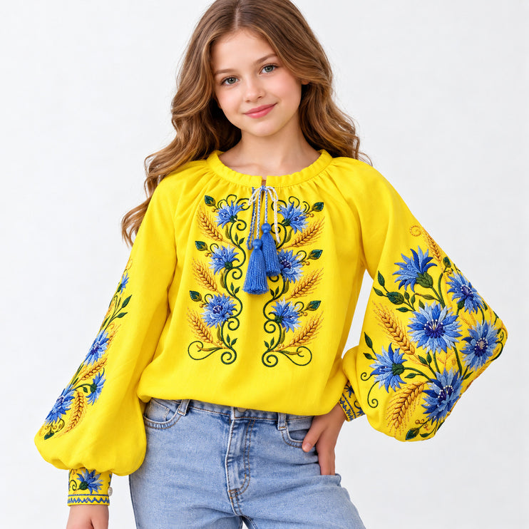Girl wearing a yellow Ukrainian embroidered vyshyvanka blouse with blue cornflower and wheat motifs and jeans