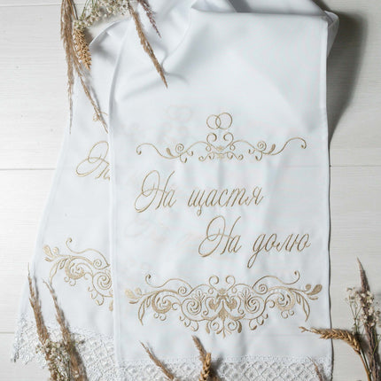 A white wedding rushnyk with gold-thread embroidery, displaying the phrase 'На щастя, На долю'.
