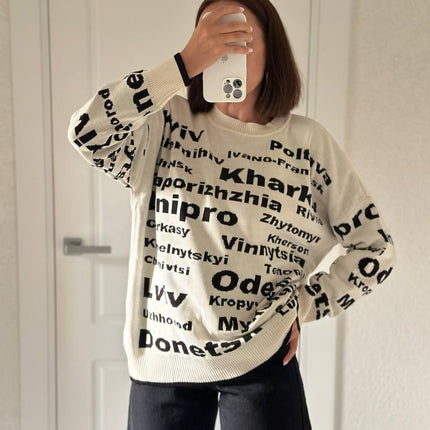 Upper-body view of a cream oversized knit sweater showing Odesa, Dnipro and Kharkiv in black letters