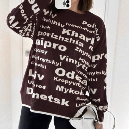 Close-up mirror selfie of a chocolate brown oversized sweater with cream Odesa and Dnipro lettering