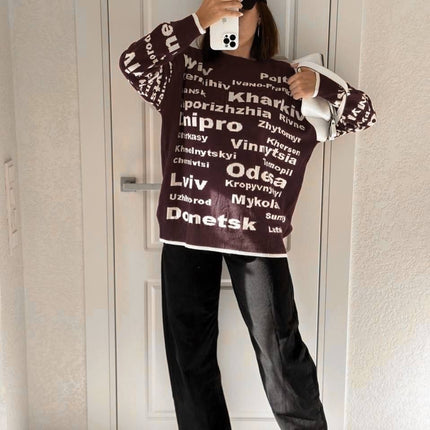 Full-length mirror view of a chocolate brown Ukrainian cities knit sweater with wide-leg jeans