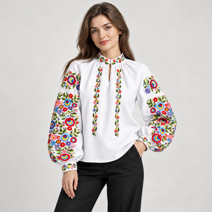 White Ukrainian embroidered blouse with stand collar, keyhole neckline and multicolor floral sleeves, worn with black trousers