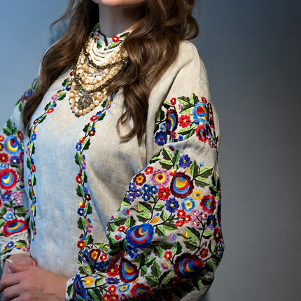 Natural linen Ukrainian blouse with floral sleeve embroidery styled with a traditional beaded necklace