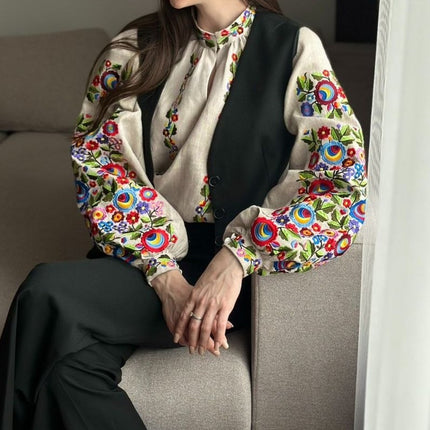 Natural linen vyshyvanka with colorful floral sleeves styled with a black vest and black trousers