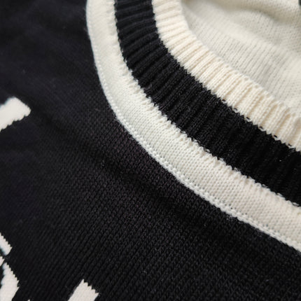 Close-up of the ribbed round neckline with contrast stripe on a black Ukrainian cities knit sweater